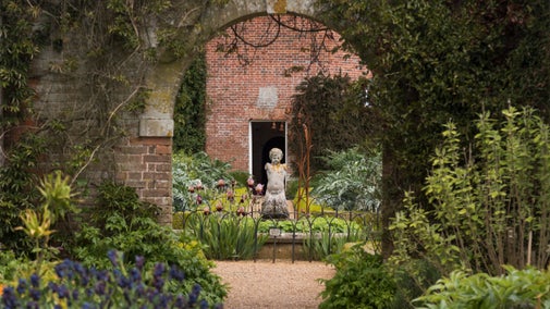 View through an arch to a decorative pond and statue at the centre of Felbrigg's Walled Garden.